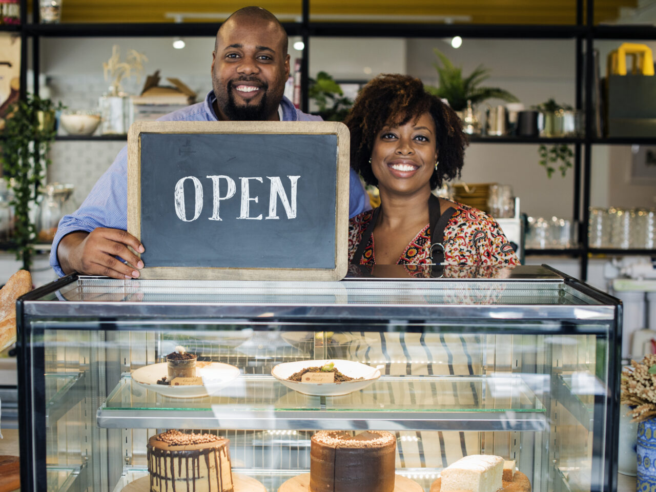 Cake cafe owners with open sign